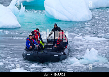 Les touristes font leur chemin à travers les flux de glace de l'Antarctique dans un zodiac. Banque D'Images