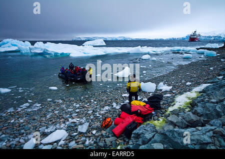 Les touristes débarquent à partir d'un zodiac pour explorer une île sauvage de glace. Banque D'Images