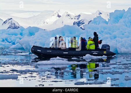Explorez les touristes icebergs bleu croisière dans un bateau gonflable. Banque D'Images