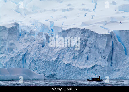 Les touristes d'explorer une zone de fracture glacier robuste dans un bateau gonflable. Banque D'Images