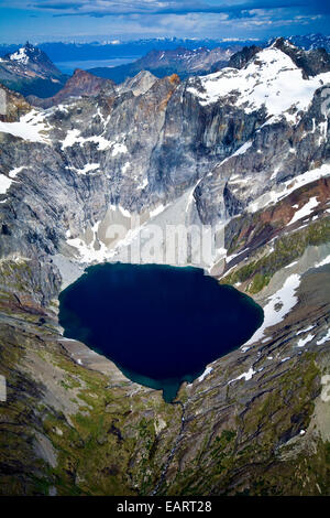 Un lac glaciaire turquoise bercé par la neige et la glace des pics drapés. Banque D'Images