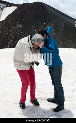 Etna, Sicile, Italie. Les touristes essaient d'allumer leurs cigarettes par un vent fort à mi-hauteur du volcan Banque D'Images