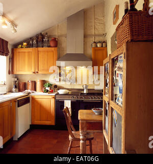 Une cuisine traditionnelle avec un plafond en pente et doté d''un ventilateur d'acier inoxydable au-dessus d'une grande cuisinière avec du bois de pin et d'un carrelage rouge, UK Banque D'Images