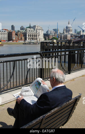 Man reading newspaper sur South Bank London UK Banque D'Images