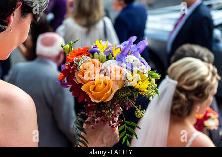 Une demoiselle détient un bouquet de brides à un mariage Orthodoxe Grec. Banque D'Images