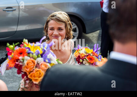 Un heureux, blushing bride avec son bouquet à un mariage Orthodoxe Grec. Banque D'Images