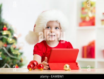 Kid girl in christmas hat with tablet pc Banque D'Images