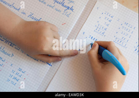 Un écolier de 10 ans est en train de faire ses devoirs de mathématiques. Banque D'Images