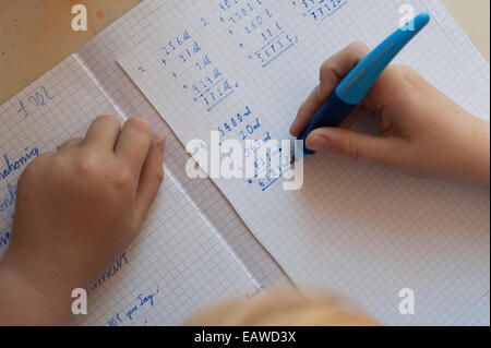 Un écolier de 10 ans est en train de faire ses devoirs de mathématiques. Banque D'Images