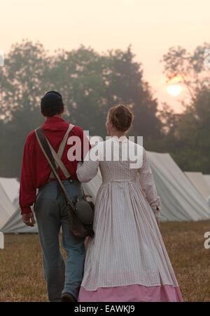 Un jeune couple habillé en civil War era clothing marche bras dessus bras dessous. Banque D'Images