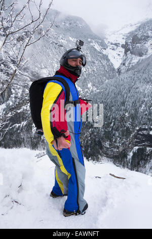 Cavalier Base Wingsuit se prépare à sauter d'une falaise dans la vallée profonde et il a l'air très nerveux. Banque D'Images