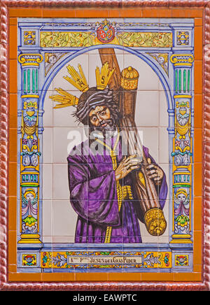 Séville - sol carrelé de céramique le Christ avec la croix par manufacture 'Campos de Séville sur la façade de l'église. Banque D'Images