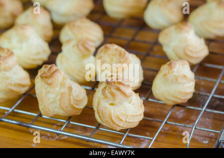 Choux frais crème sur une grille de refroidissement sur table en bois Banque D'Images