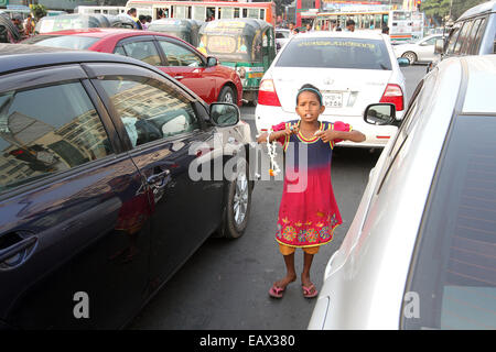 Dhaka Novembre 2014. Un enfant sur le côté de la route, tente de vendre des fleurs à l'adoption de navetteurs dans les voitures et les bus. Banque D'Images