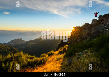 Randonneur avec bras levés au sommet d'une montagne au lever du soleil, Pico do Arieiro, Madère Banque D'Images