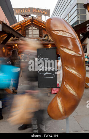 Witch House Grand allemand surdimensionnée avec Bratwurst sign Marchés de Noël et shoppers, Manchester, UK Banque D'Images