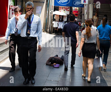 Mendiant handicapé sur Silom Road, Bangkok, Thaïlande, les gens de la classe moyenne par pied. Banque D'Images