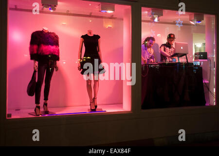 Deux jeunes DJs jouent la musique forte provenant de l'intérieur d'une fenêtre d'un détaillant de mode à Carnaby Street, Londres. Banque D'Images