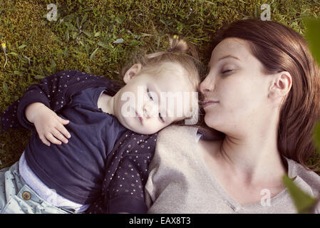 Mère et fille bébé sieste sur l'herbe Banque D'Images