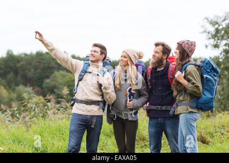Groupe d'amis avec des sacs en tenant selfies Banque D'Images