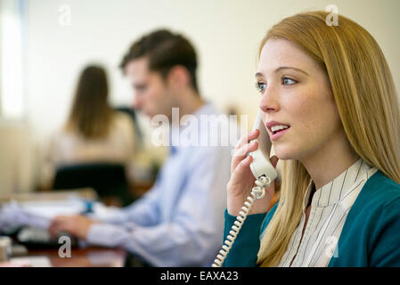 Femme à l'aide de téléphone fixe le in office Banque D'Images