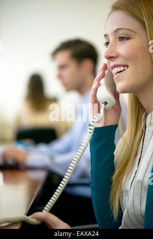 Femme à l'aide de téléphone fixe le in office Banque D'Images