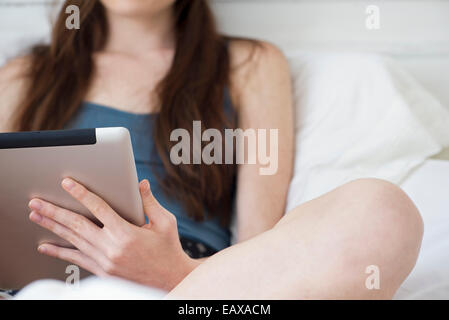 Woman using digital tablet in bed Banque D'Images