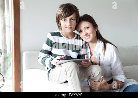 La mère et le fils assis ensemble sur canapé with digital tablet