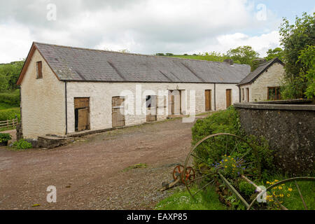 De vastes bâtiments stable peint en blanc avec red dirt track et grappes de végétation verte dans les exploitations agricoles dans les régions rurales du pays de Galles. Banque D'Images