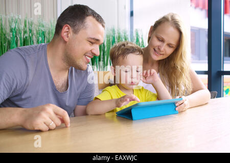 Une famille heureuse de trois avec tablet computer in cafe Banque D'Images