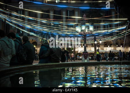 Bacelona, Espagne. 21 Nov, 2014. Le 21 novembre, 2014 - Les gens s'asseoir sur la fontaine sous les lumières de Noël sur la Plaza Real, une attraction touristique bien connue, comme Barcelone commence la période des fêtes - Les fêtes de fin d'année 2014 est en cours à Barcelone comme les lumières de Noël et les arbres sont mis en marche dans les rues Crédit : Matthias Rickenbach/ZUMA/ZUMAPRESS.com/Alamy fil Live News Banque D'Images