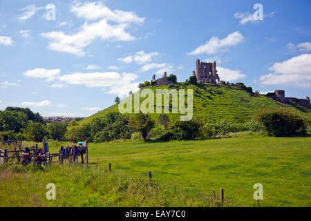 Château de Corfe vus d'un train à vapeur qui passe comme un groupe de marcheurs vague comme elles attendent pour traverser la ligne Dorset England UK Banque D'Images