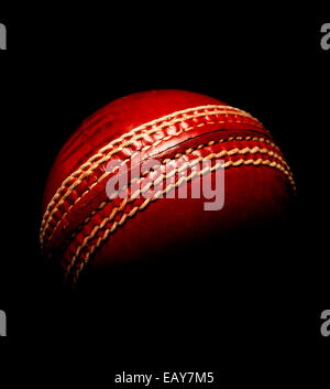 Cricket Ball en cuir rouge sur noir Banque D'Images
