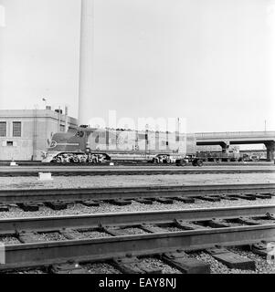 Cette photographie historique capture la locomotive électrique de passagers Atchison, Topeka et Santa Fe Diesel Electric No. 13 positionnée devant une cheminée. La locomotive représente la technologie ferroviaire américaine du milieu du XXe siècle et l'héritage de l'ATSF Railway Company. Banque D'Images