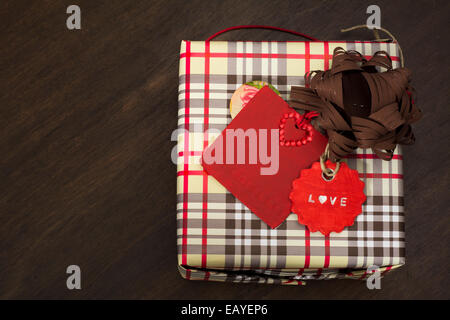 Présente enveloppés dans du papier et du ruban à carreaux avec étiquette rouge sur fond de bois Banque D'Images