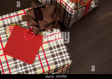 Présente enveloppés dans du papier à carreaux et ruban en pointillés avec l'étoile rouge sur fond de bois Banque D'Images