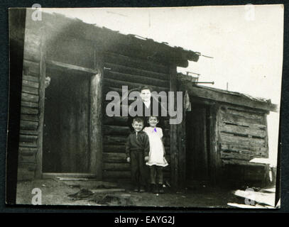 Urss - circa 1960 : une ancienne photo, maman avec deux enfants près de la maison, vers 1960 Banque D'Images