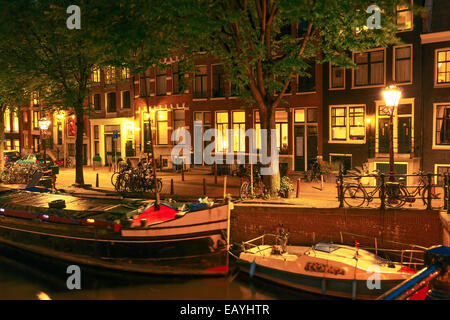 Nuit vue sur la ville d'Amsterdam canal, pont et maisons typiques, des bateaux et des vélos, en Hollande, aux Pays-Bas. Banque D'Images