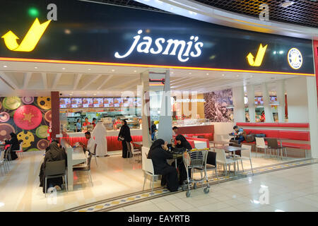 Avoir un en-cas à ce fast food avant de monter à bord de l'avion à la salle d'embarquement à l'Aéroport International de Bahreïn, Bahreïn, au Moyen-Orient. Bahreïn a une population de plus de 55  % des immigrants et a eu des élections générales en ce jour. Banque D'Images