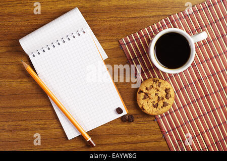 Ouvrir le bloc-notes et tasse de café avec des biscuits au chocolat sur la table en bois Banque D'Images