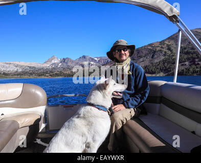 L'homme et le chien en bateau dans le lac sacoche qui transporte les randonneurs à et de sentier à 20 Lacs Banque D'Images