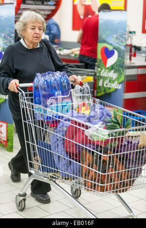 Femme âgée shopping chariot poussant chariot de supermarché Prague République tchèque Europe femme senior Shopper plus vieux client panier marchandises chariot magasin Banque D'Images