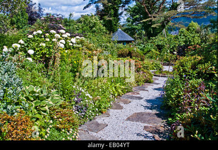 Abri luxuriant jardin avec arbustes et plantes en fleurs en frontières soleil d'été, Plockton, Wester Ross, les Highlands écossais Banque D'Images