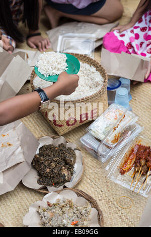 La main de l'offrant de la nourriture. Panier de riz grillé et de la viande à l'intérieur des tubes de bambou, connu sous le nom de Pa'piong, un plat traditionnel à Tana Banque D'Images