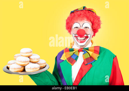 Clown avec crêpes de Berlin sur fond jaune Banque D'Images