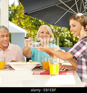 Grand-mère qui sert le déjeuner en petit-fils à table avec une louche Banque D'Images