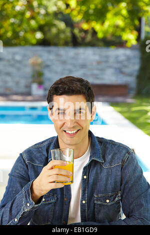 Homme heureux de boire du jus d'orange frais en été Banque D'Images