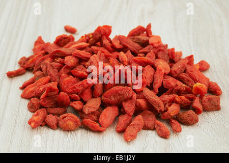 Tas de baies de goji séchées sur une table en bois Banque D'Images