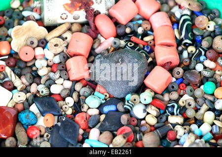 De nombreuses et multiformes pour faire collier perles en pierre situé sur un seau en plastique vert sur le trottoir. Pokhara-Nepal. Banque D'Images