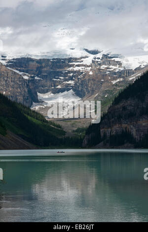 Lake Louise en Alberta (Canada) : un canot glisse sur les eaux du glacier dans la lumière du matin. Banque D'Images